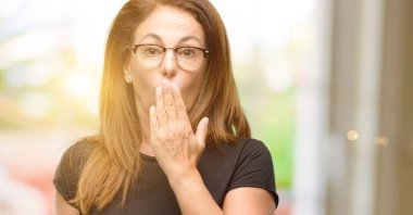 Orta yaş kadın siyah gömlek ve gözlük şok ağzına kapsar, sessizlik ve hata kavramlar, korkmuş ifade utangaç, görünüyor