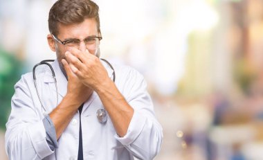 Genç yakışıklı Doktor adam bir şey pis ve iğrenç kokulu izole arka plan, dayanılmaz koku, holding nefes burun parmaklar ile. Kötü kokuyor kavramı.