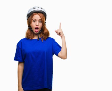 Başarılı fikirle izole arka plan işaret parmağı üzerinde bisikletçi kask giyen genç güzel kadın. Çıktıktan ve mutlu. Bir numara.