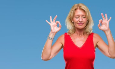 Orta yaş sarışın kadın izole arka plan üzerinde dinlenmek ve gülümseyen gözlerle parmak ile meditasyon jest yapıyor kapalı. Yoga kavramı.