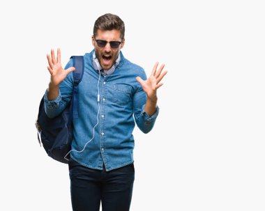 Üzerinde kulaklık ve sırt çantası giyen genç yakışıklı turist adam arka plan deli kutluyor izole ve crazy arms ile başarı için kaldırdı ve heyecanlı çığlık gözler kapalı. Kazanan kavramı