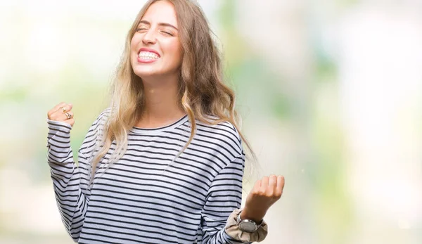 美丽的年轻金发碧眼的女人穿着条纹毛衣在孤立的背景非常高兴和兴奋做赢家的手势与手臂抬起 面带微笑 尖叫着要成功 庆祝理念 — 图库照片