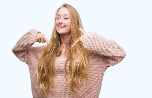 金发少女穿着粉红色的毛衣看起来自信与微笑在脸上 指着自己与手指自豪和快乐 — 图库照片
