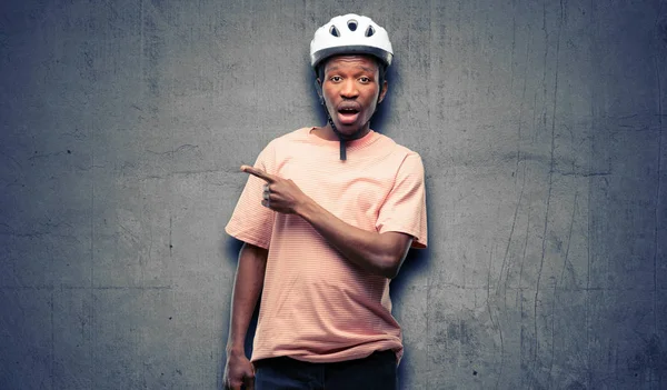 Black man wearing bike helmet pointing away side with finger