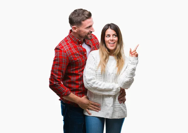 カメラを見ている側の手と指で指すの顔に大きな笑みを浮かべて隔離された背景に冬のセーターを着ている愛の若いカップル — ストック写真