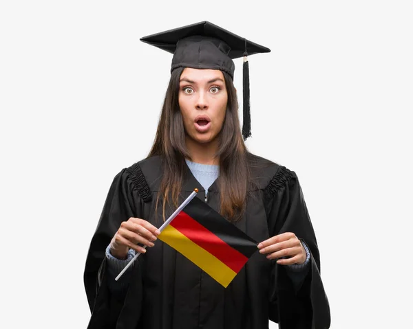 Mujer Hispana Joven Vistiendo Uniforme Graduado Sosteniendo Bandera Alemania Asustada —  Fotos de Stock