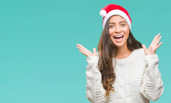 若いアラブ女性のクリスマスの帽子をかぶって狂気を祝う背景を分離した腕を上げると成功のためびっくりし 叫んで興奮して目を開きます 勝者の概念 — ストック写真
