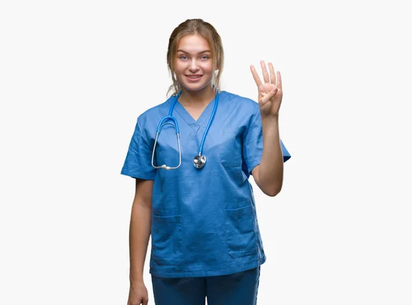 年轻的高加索医生妇女穿着外科医生制服在孤立的背景显示和指向与手指第四 同时微笑着自信和快乐 — 图库照片