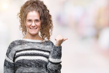 Güzel esmer kıvırcık saçlı Genç kız arıyorum ve başparmak yanında yukarıyı mutlu yüz ile gülümseyen izole arka plan üzerinde gözlük.