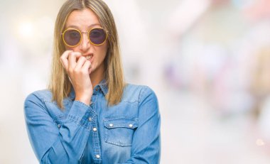 Tırnak ısırma dudaklarından eller genç güzel kadın stresli ve gergin ile izole arka plan üzerinde güneş gözlüğü takıyor. Anksiyete sorunu.