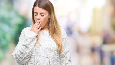 Genç güzel kadın rahat beyaz kazak izole arka plan üzerinde esneme yorgun kapsayan ağız el ile sıkılmış. Restless ve uyku hali.