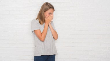 Yüzünü elleriyle ağlayarak süre kapsayan üzgün ifade ile beyaz tuğla duvarın üzerinden güzel ve genç birbayan. Depresyon kavramı.