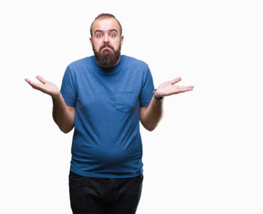 Genç beyaz hipster adam izole arka plan clueless ve şaşkın bir ifadeyle kollar ve eller kaldırdı. Şüphe kavramı.