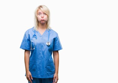 Young beautiful blonde doctor woman wearing medical uniform over isolated background puffing cheeks with funny face. Mouth inflated with air, crazy expression. clipart