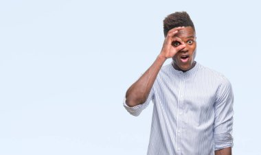 Sürpriz yüz, göz parmaklarının arasından seyir ile ok jest yapıyor izole arka plan üzerinde genç Afro-Amerikan adam şok. İmansız ifade.