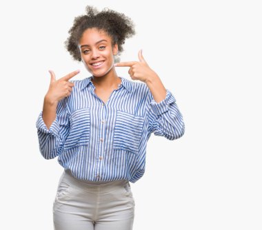 Kendinden emin gösterilen ve işaret parmakları diş ve ağız ile gülümseyen izole arka plan üzerinde genç afro Amerikalı kadın. Sağlık kavramı.