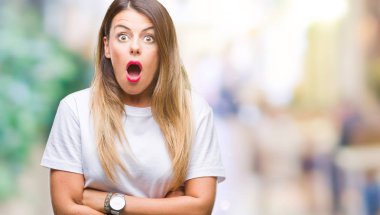 Genç güzel kadın rahat beyaz t-shirt üzerine izole arka plan korkuyor ve sürpriz ifade ile şok korku ve heyecan yüz.