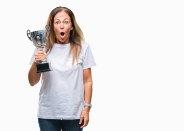 Orta yaş İspanyol kazanan kadın üzerinde Ödülü holding kupa kutlama arka plan bir sürpriz yüz, korkuyor ve heyecanlı korku ifadesi ile şok korkmuş izole