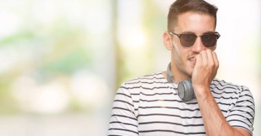 Yakışıklı genç adam stresli ve gergin ile seyir kulaklıklar giyen tırnak ısırma dudaklarından eller. Anksiyete sorunu.
