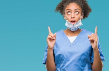Genç afro Amerikalı doktor kadın izole arka plan üzerinden hayran ve yukarıya bakıp parmakları ile işaret şaşırttı ve silah kaldırdı.