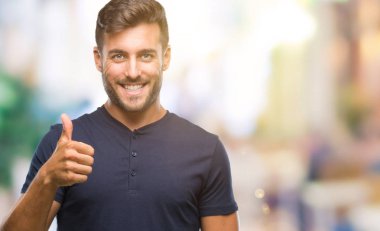 Yakışıklı delikanlı hareketi el ile mutlu yaşasın yapıyor izole arka plan üzerinde. Kameraya bakarak başarı gösteren ile ifade onaylama.