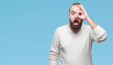 Sürpriz yüz, göz parmaklarının arasından seyir ile ok jest yapıyor izole arka plan üzerinde kış kazak giyen genç beyaz hipster adam şok. İmansız ifade.