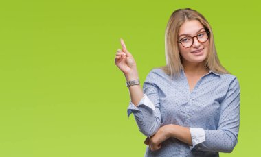 Yüzünde kocaman bir gülümseme ile izole arka plan üzerinde gözlük takan Genç beyaz iş kadını kameraya bakarak yan el ve parmak ile işaret.