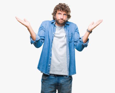 Yakışıklı İspanyol modeli adam izole arka plan clueless ve şaşkın bir ifadeyle kollar ve eller kaldırdı. Şüphe kavramı.
