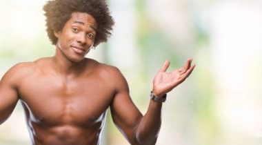Afro Amerikalı gömleksiz adam çıplak vücut üzerinde gösterilen arka plan clueless ve şaşkın bir ifadeyle kollar ve eller kaldırdı izole. Şüphe kavramı.