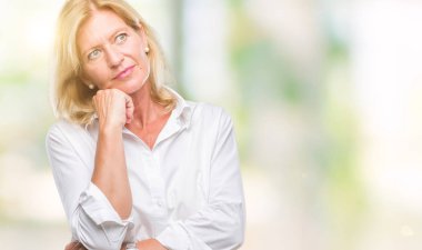 Orta yaş sarışın iş kadını elle çene düşünme hakkında soru, dalgın ifade izole arka plan üzerinde. Düşünceli yüzüyle gülümsüyor. Şüphe kavramı.