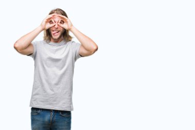 Yakışıklı delikanlı, dilini parmaklarının arasından baktığını yapışmasını dürbün gibi ok jest yapıyor izole arka plan üzerinde uzun saçlı. Deli ifade.