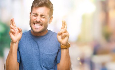 Yakışıklı delikanlı geçiş parmakları umut ve gözleri kapalı ile gülümseyen izole arka plan üzerinde. Şans ve batıl kavramı.