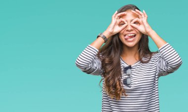 Genç güzel Arap kadın dilini, parmaklarının arasından baktığını yapışmasını dürbün gibi ok jest yapıyor izole arka plan üzerinde güneş gözlüğü takıyor. Deli ifade.