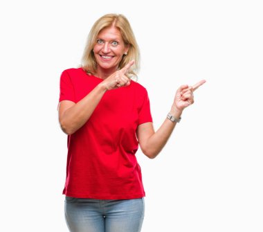 Orta yaş sarışın kadın gülümseyerek ve iki elleri ve parmakları ile tarafına işaret kamera bakarak izole arka plan üzerinde.