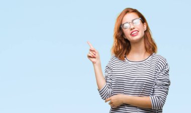 Kameraya bakarak yan el ve parmak ile işaret izole arka yüzünde, kocaman bir gülümseme ile gözlük takan genç güzel kadın.