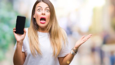 Akıllı telefon boş ekran büyük gülümseme ile çığlık zaferini kutluyor ve ellerini kaldırdı izole arka plan çok mutlu ve heyecanlı, kazanan ifade üzerinde gösterilen genç güzel kadın