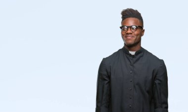 Genç Afro-Amerikan rahip adam görünümlü yan ve dik dik bakma uzağa düşünce gülümseyen izole arka plan.