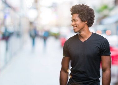 Uzak tarafına yüzünde, doğal ifade gülümseme ile seyir izole arka plan üzerinde Afro Amerikalı adam. Kendine güvenen gülüyor.