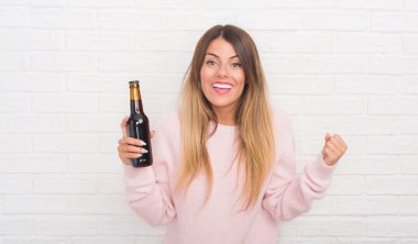 Duygu tezahürat Yound yetişkin kadın gurur çığlık ve zafer ve başarı çok heyecanlı, kutluyor bira holding beyaz tuğla duvar