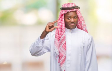 Geleneksel keffiyeh izole arka plan gülümseyen ve süre seyir ve kamera boyutu işaret parmaklarıyla yapıyor el ile kendinden emin eller üzerinde giyen genç Arapça Afrika adam. Ölçü kavramı.