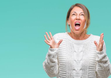 Üzerinde kış kazak giyen orta yaş üst düzey İspanyol kadın arka plan deli izole ve deli bağırarak ve agresif ifade ve silah kaldırdı bağırıyor. Hayal kırıklığı kavramı.