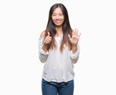 Genç Asyalı kadın gösterilen ve parmakları ile işaret izole arka plan üzerinde kendinden emin ve mutlu gülümseyerek süre 6 numara.