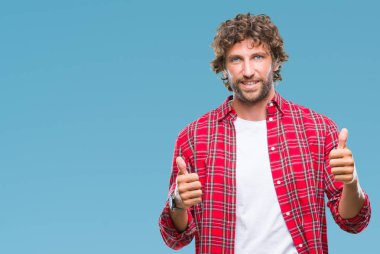 İzole arka plan başarı işareti el ile olumlu hareketi yaparken yakışıklı İspanyol modeli adam başparmak gülümseyen ve mutlu. Neşeli bir ifadeyle, kazanan jest kameraya bakıyor.