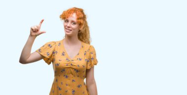 Gülümseyen genç Kızıl saçlı kadın ve süre seyir ve kamera boyutu işaret parmaklarıyla yapıyor el ile kendine güvenen el hareketi. Ölçü kavramı.