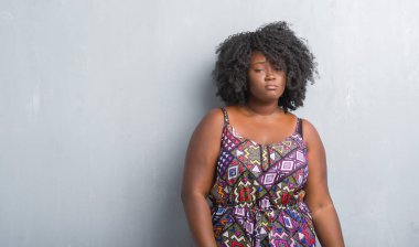 Kızgın ve korkmuş ağlıyor genç Afro-Amerikan kadın depresif renkli elbise gri grunge duvar ve sıkıntı, endişe. Üzgün ifade.