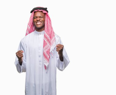 Geleneksel keffiyeh üzerinde giyen genç Arapça Afrika adam arka plan çok mutlu ve heyecanlı kaldırdı, silah ile kazanan jest yapıyor gülümseyen ve başarı için çığlık izole. Kutlama kavramı.