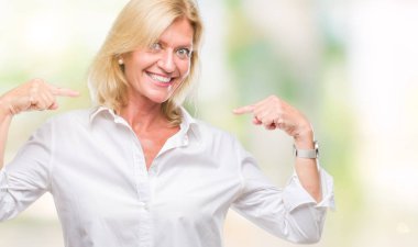 Orta yaş sarışın iş kadını yüzünde gülümseme ile kendinden emin görünüyorsun, kendini gururlu ve mutlu parmakları ile işaret izole arka plan üzerinde.