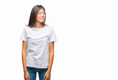 Genç Asyalı kadın uzak tarafına yüzünde, doğal ifade gülümseme ile seyir izole arka plan üzerinde. Kendine güvenen gülüyor.