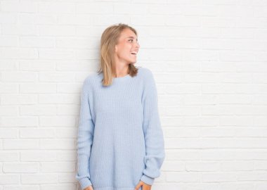 Güzel genç kadın üzerinde beyaz tuğla duvar uzak tarafına gülümseme ile yüzünde, doğal ifade arıyorum. Kendine güvenen gülüyor.