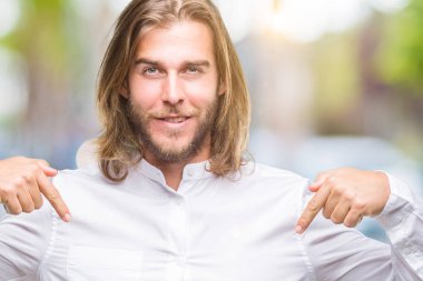 Yüzünde gülümseme ile kendinden emin görünüyorsun, kendini gururlu ve mutlu parmakları ile işaret izole arka plan üzerinde uzun saçlı yakışıklı delikanlı.